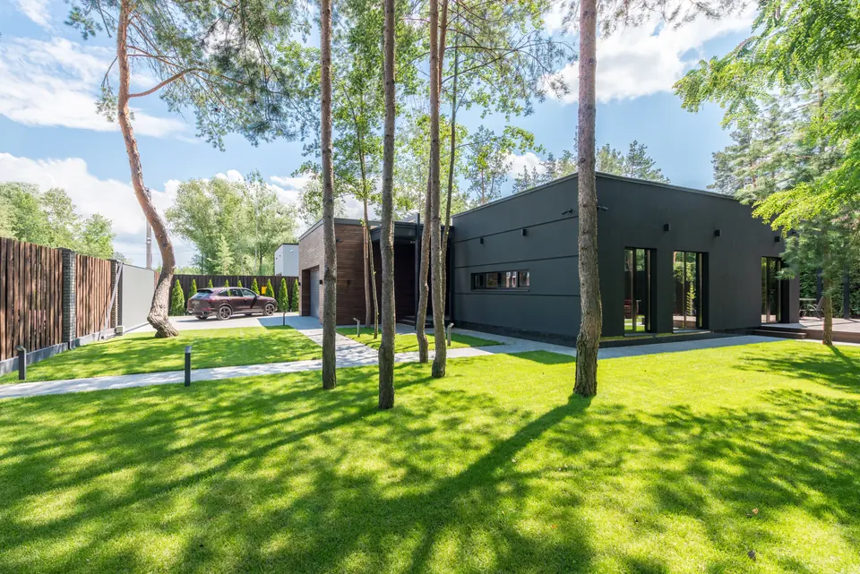 Moderner Garten mit gepflegtem Rasen, Bäumen und klarer Architektur.